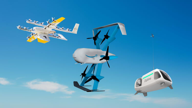 A composite rendering of three delivery drones in flight against a blue sky: a white-and-yellow Google Wing drone, a blue-and-white Amazon hexacopter with the Amazon smile logo, and a Zipline drone with a suspended white delivery pod.