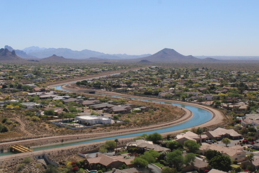Aerial view of the Central Arizona Project canal curving through desert suburban landscape with mountains in the background