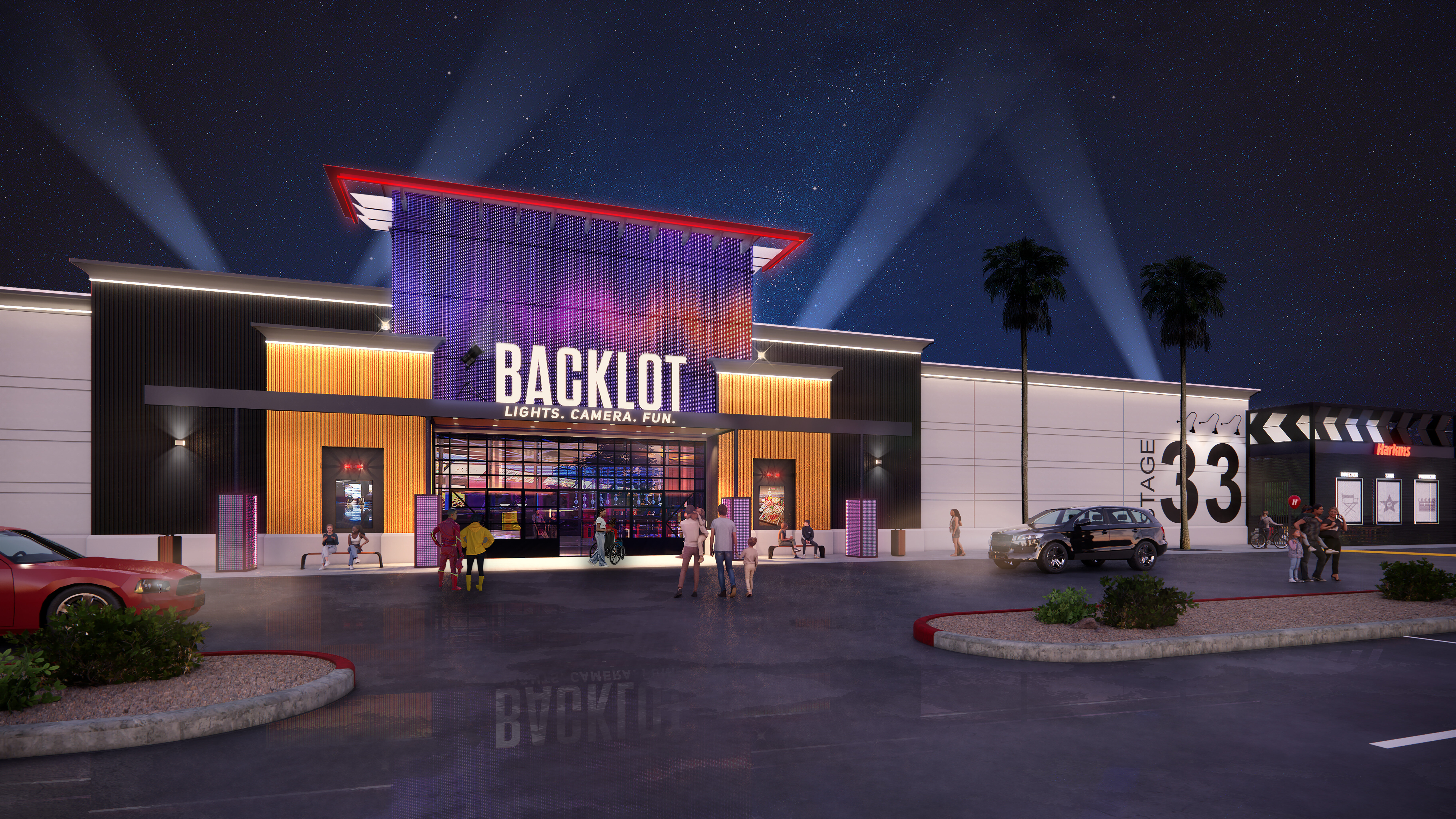 Architectural night rendering of the Backlot entertainment venue exterior with Stage 33 and Harkins signage, spotlights fanning into a starry sky, and pedestrians in the parking lot