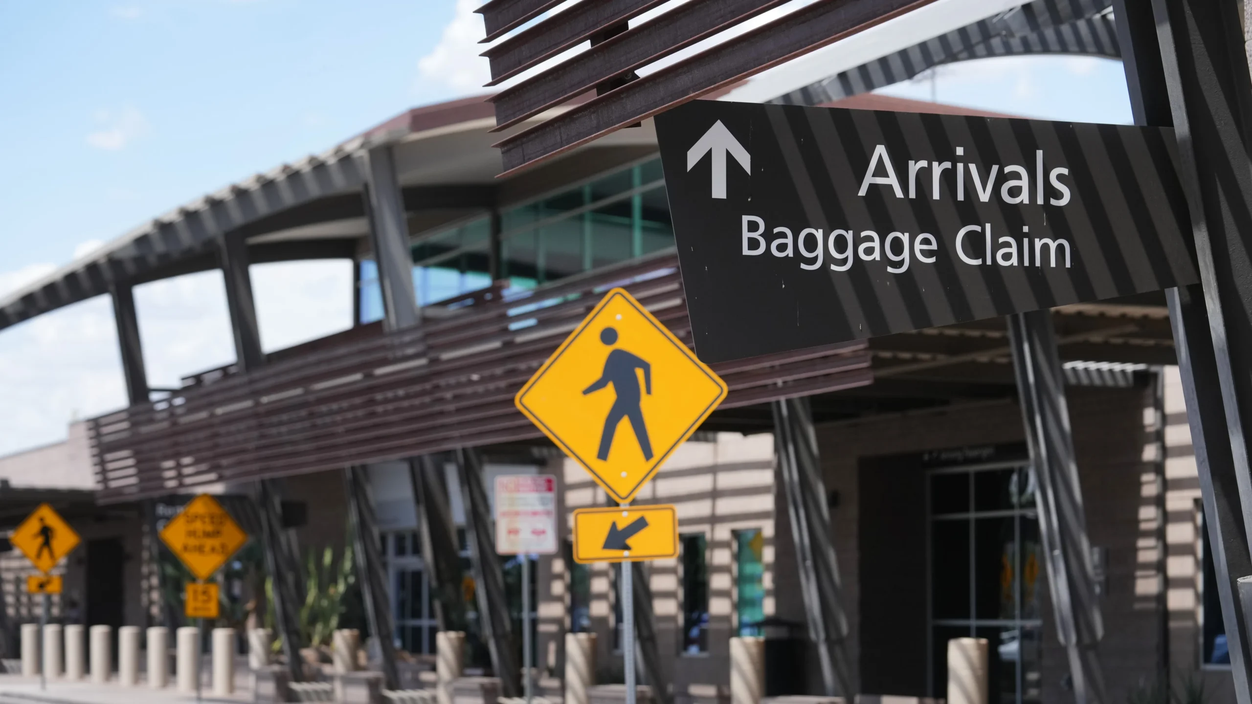 Arrivals and baggage claim signage outside the Mesa Gateway Airport terminal with a modern covered canopy in the background