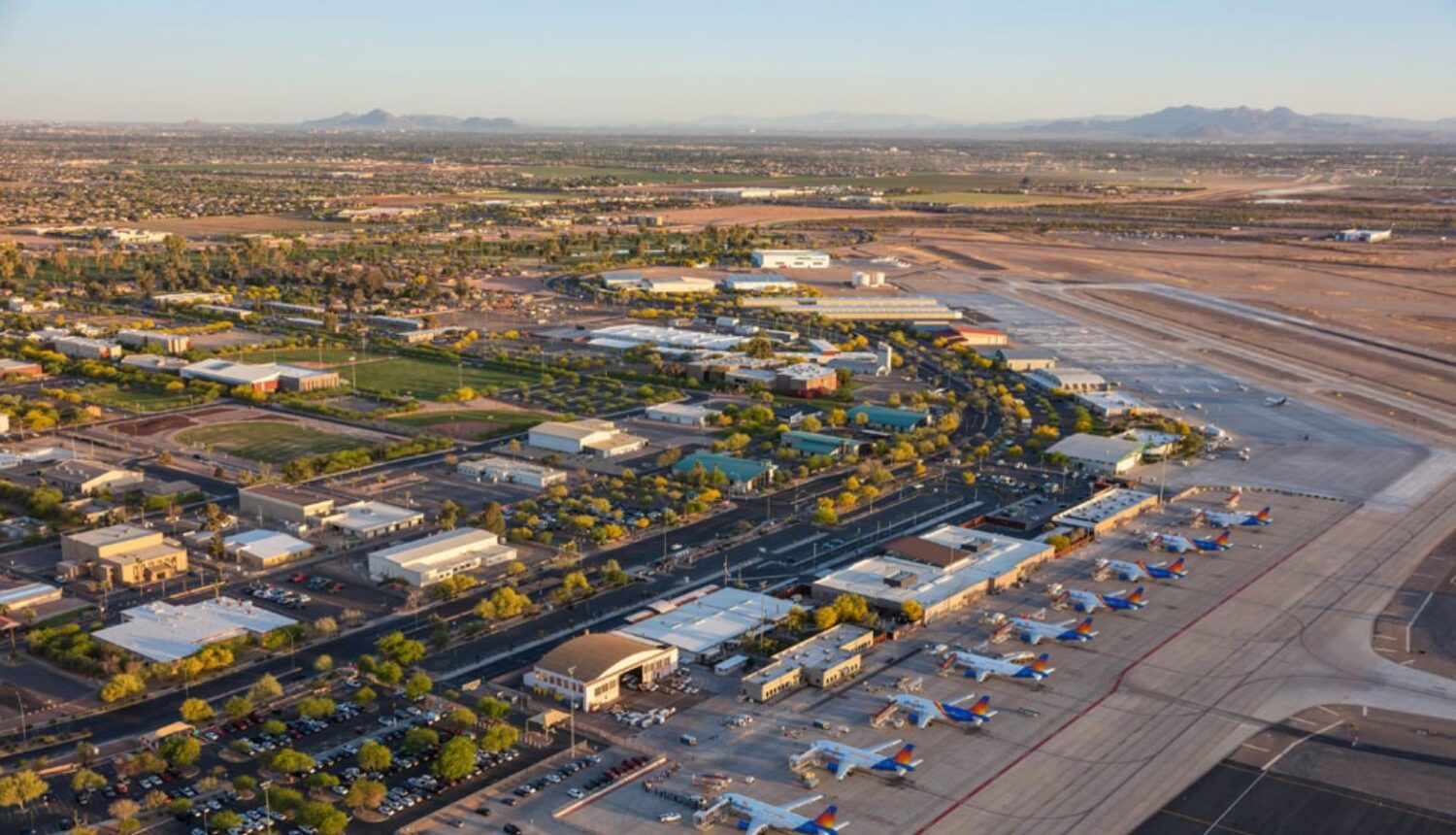 Aerial photograph of Mesa Gateway Airport showing the terminal building, multiple Southwest Airlines aircraft parked at gates, taxiways, runways, and surrounding suburban desert landscape with mountains on the horizon.