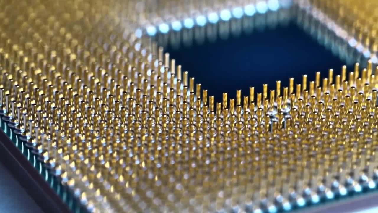 Extreme macro photograph of a CPU processor gold-plated pin array surrounding a dark central die cavity, shot at a low angle that shows the dense grid of metallic contacts.