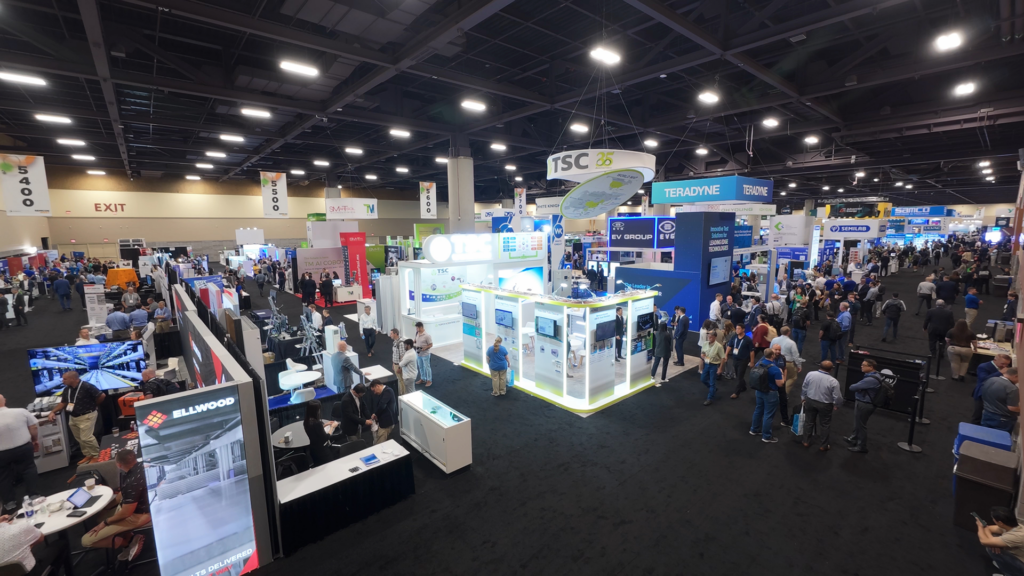Overhead view of a busy semiconductor industry trade show exhibition hall with booths for TSC, Teradyne, EV Group, Ellwood, Semilab and other companies, with crowds of attendees walking the floor.